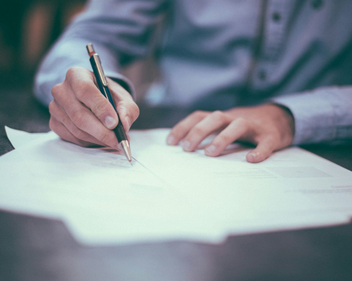 Person signing a document with a pen